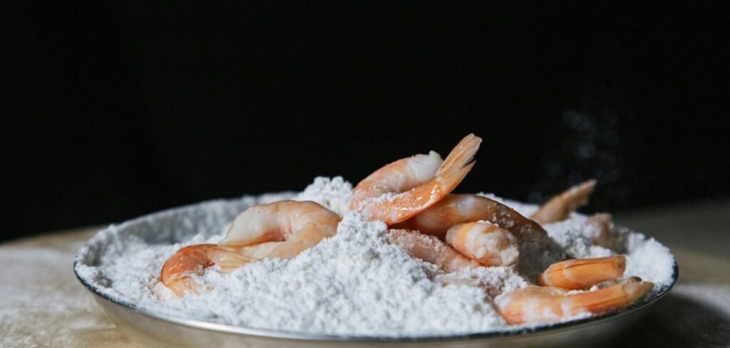 A close-up view of fresh shrimps placed on a bed of flour, ideal for food photography and culinary themes.